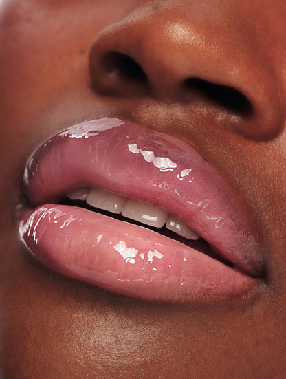 Macro close-up of smooth, glossy lips with Lanolips Milkshake Ceramide Balm in Raspberry Crumble, showing a hydrated finish and sheer raspberry tint