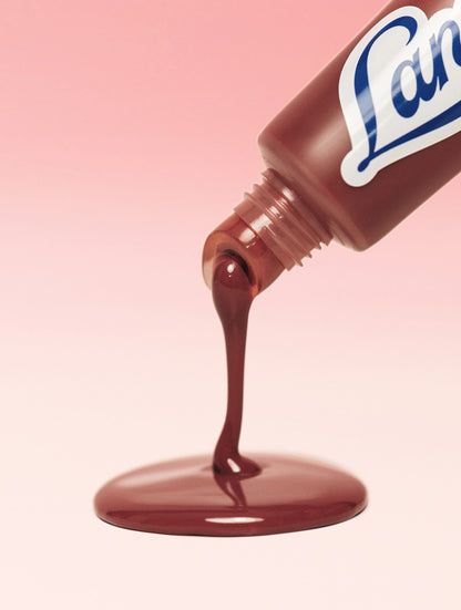 Lanolips Ceramide Milkshake Balm in Caramel Melt dispensing glossy, creamy balm showing a rosy-caramel nude tint