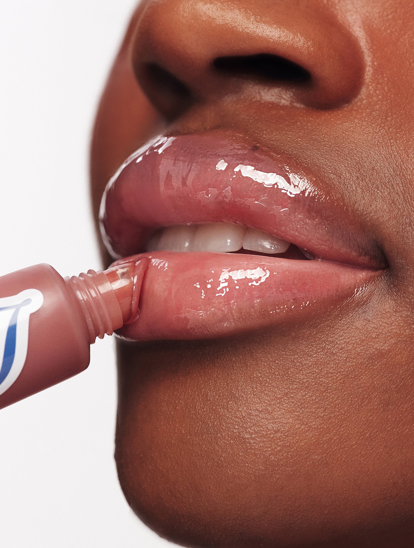 Close-up of lips applying Lanolips Ceramide Milkshake Balm in Caramel Melt, showing glossy hydrated lips with a rosy-caramel nude tint