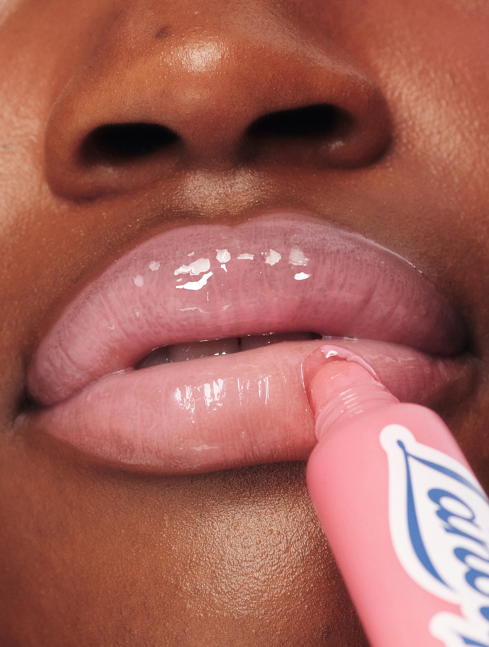 Close-up of a model applying Lanolips Milkshake Ceramide Balm in Strawberry Bubble, showing soft pink, glossy lips with a smooth, hydrated finish.