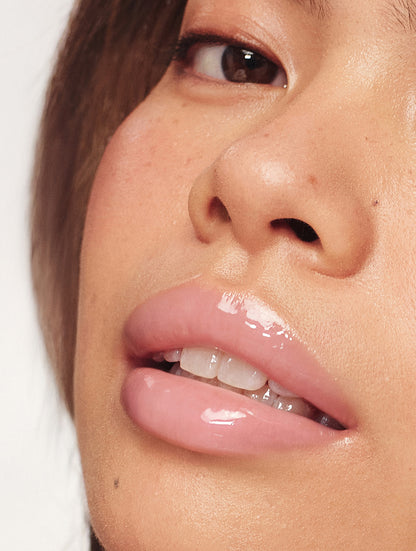 Close-up of a model’s lips wearing Lanolips Milkshake Ceramide Balm in Strawberry Bubble, showing a glossy pink finish and hydrated, smooth texture.