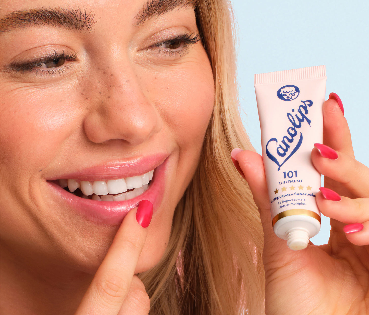 Model holding the lanolips 101 ointment in her hand and applying it her lips.