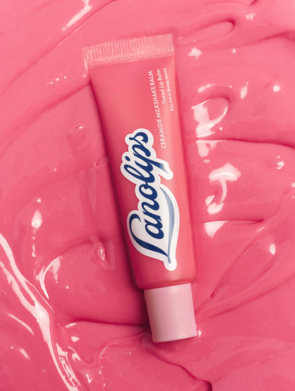 Lanolips Milkshake Ceramide Balm in Strawberry Bubble tube placed on a glossy pink balm texture background, highlighting its smooth, hydrating formula.